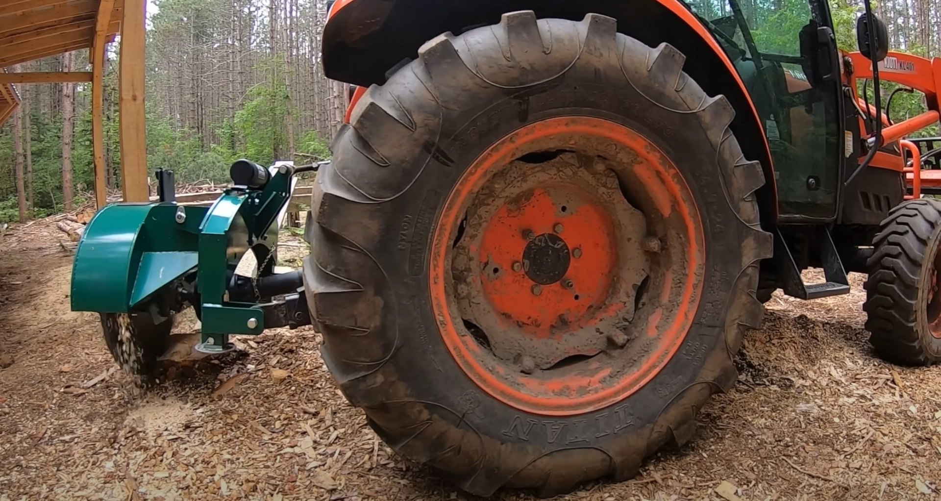 Professional Tree Service Equipment - Heavy-duty machinery for comprehensive tree care and stump removal Professional forestry equipment showing orange tractor with large tire and green stump grinder attachment in wooded area